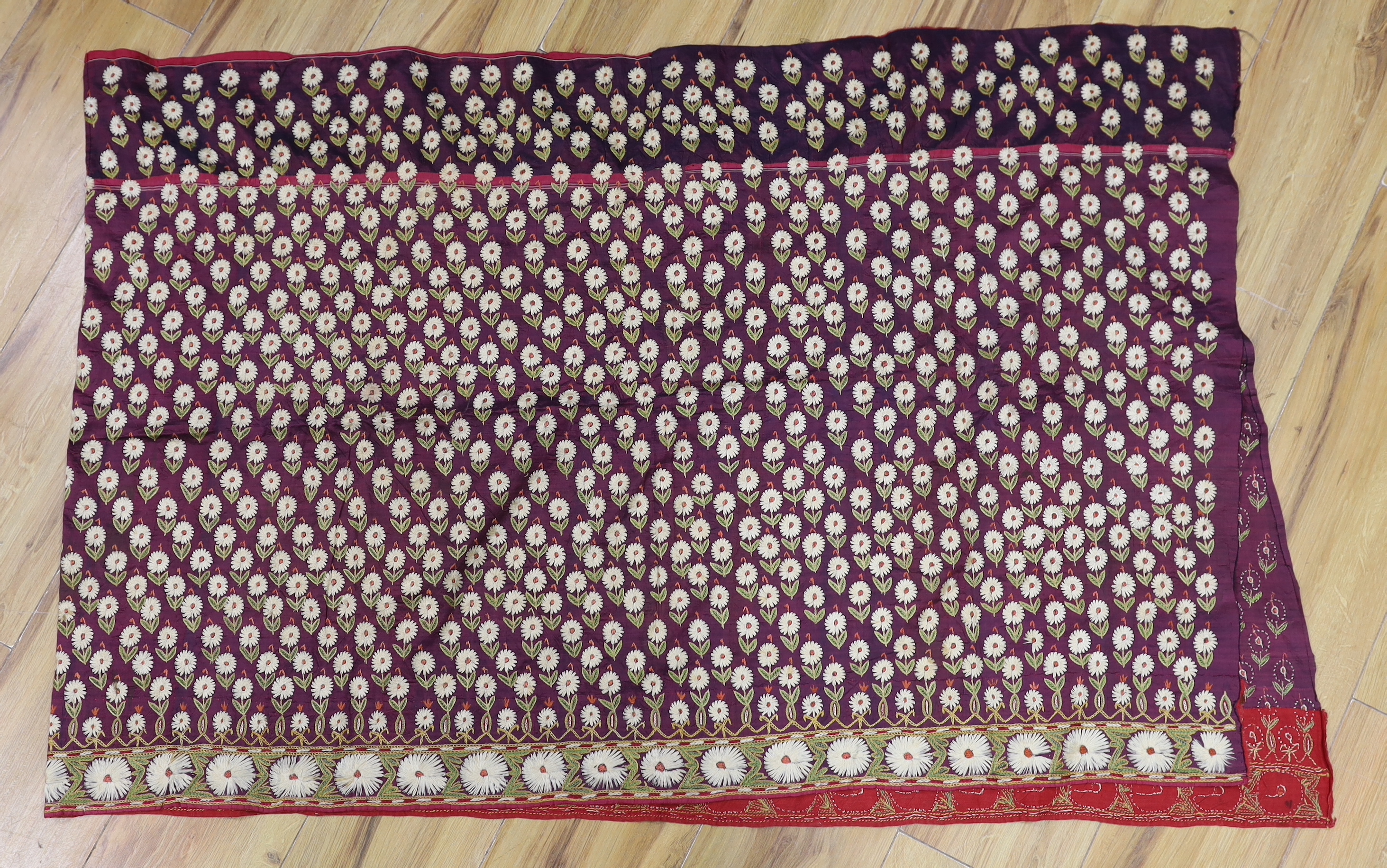 An Indian embroidered panel, a small linen embroidered panel possibly Turkish, a maroon silk length of fabric, heavily embroidered with all over flower motifs, possibly cut from a sari, together with a handwoven linen em